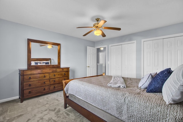 bedroom with ceiling fan, light colored carpet, and multiple closets