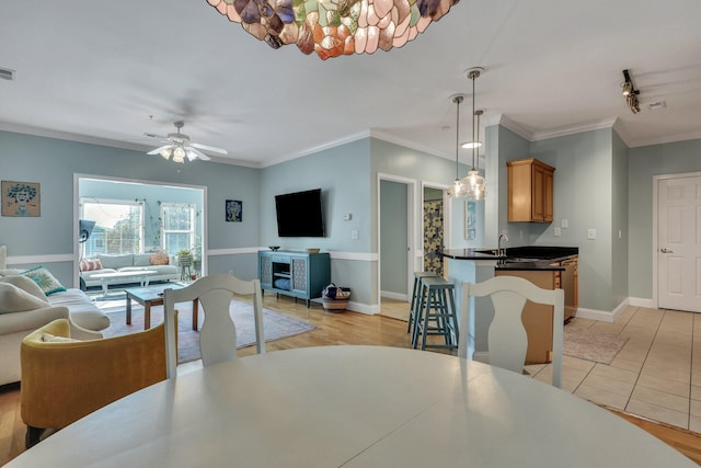 dining area with ceiling fan, crown molding, and light tile patterned flooring