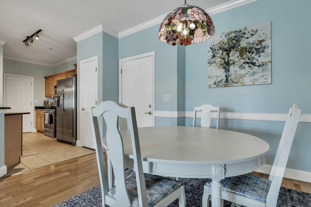 dining room featuring light wood-type flooring, rail lighting, and ornamental molding