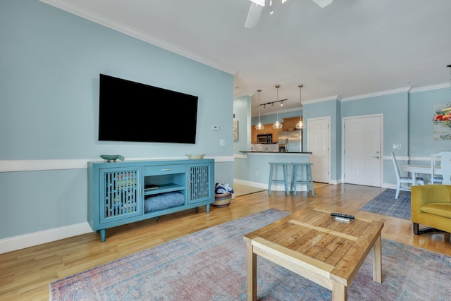 living room featuring hardwood / wood-style flooring, ceiling fan, and crown molding