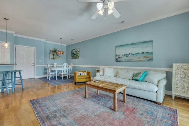 living room with ceiling fan, crown molding, and hardwood / wood-style flooring