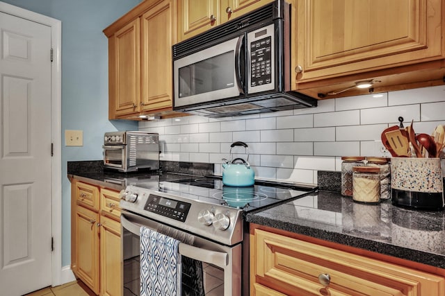 kitchen featuring light tile patterned floors, backsplash, dark stone counters, and stainless steel electric range