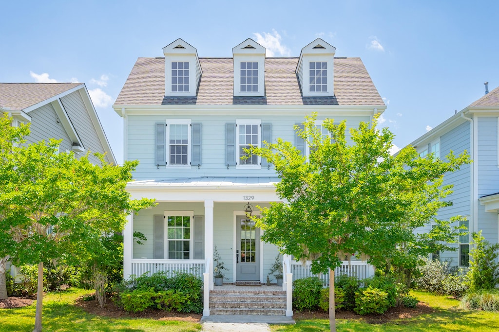 new england style home with a porch and a front lawn