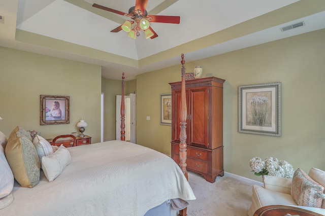 bedroom with ceiling fan, a tray ceiling, and light carpet