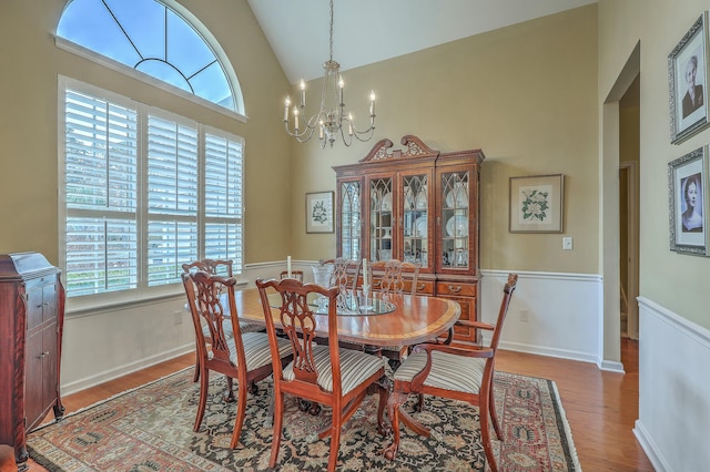 dining space with an inviting chandelier, hardwood / wood-style flooring, and high vaulted ceiling