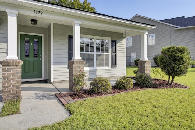 entrance to property featuring a lawn and a porch