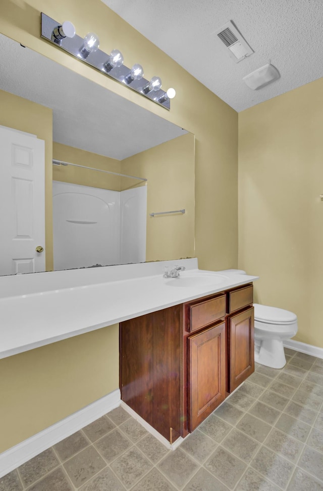 bathroom featuring vanity, a textured ceiling, toilet, and a shower