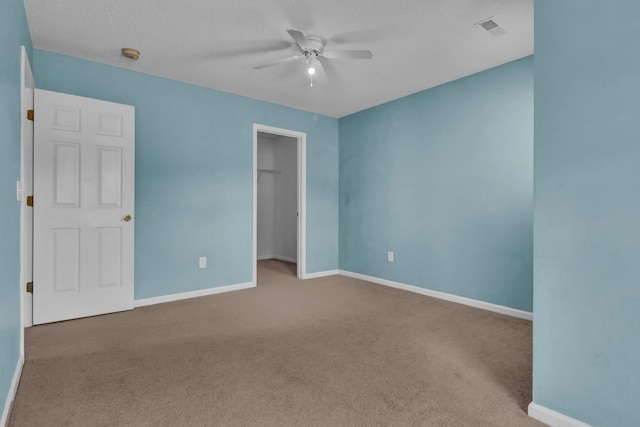 carpeted spare room featuring a textured ceiling and ceiling fan