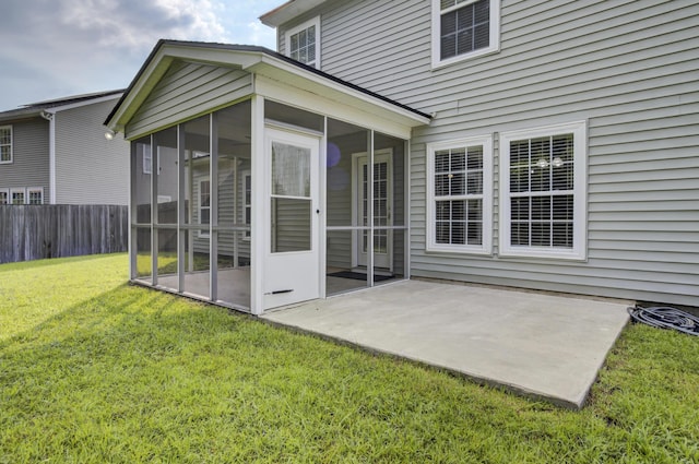 back of property with a lawn, a sunroom, and a patio