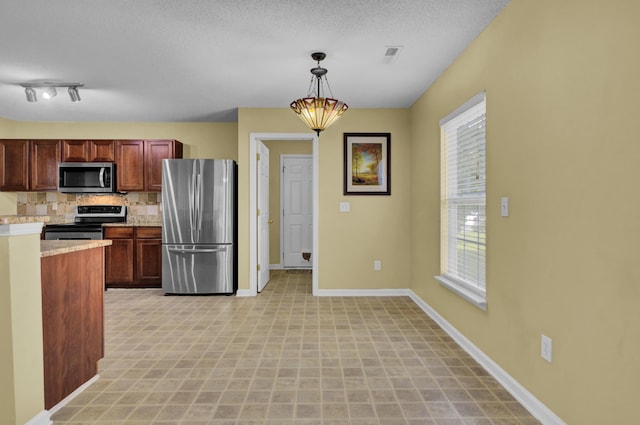 kitchen featuring pendant lighting, tasteful backsplash, appliances with stainless steel finishes, and a textured ceiling