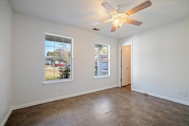 unfurnished room with ceiling fan and a textured ceiling