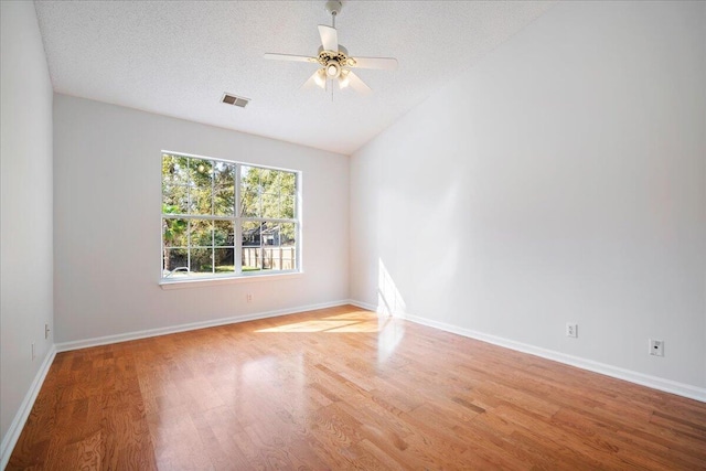 empty room with light wood-type flooring, lofted ceiling, a textured ceiling, and ceiling fan