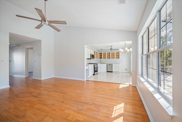 unfurnished living room with light hardwood / wood-style floors, a textured ceiling, and high vaulted ceiling