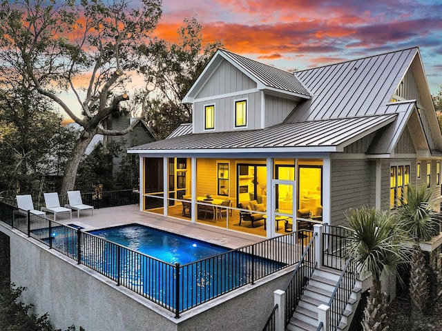 back house at dusk featuring a patio area and a fenced in pool