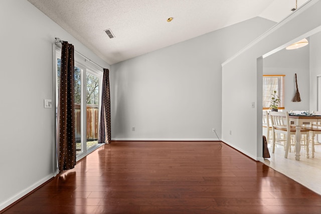 unfurnished room featuring lofted ceiling, baseboards, and wood finished floors