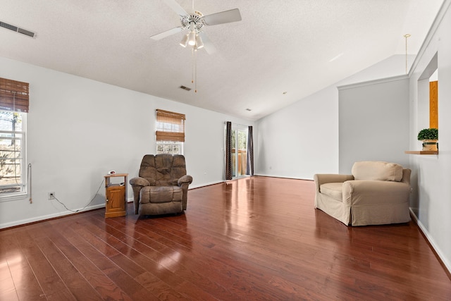 living area with visible vents, vaulted ceiling, a wealth of natural light, and wood finished floors