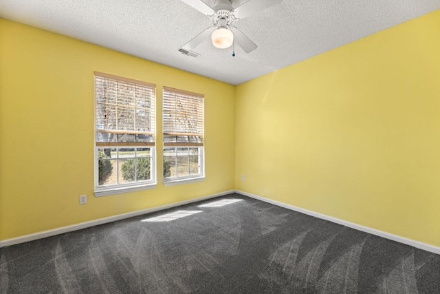 spare room featuring a textured ceiling, dark colored carpet, visible vents, and baseboards