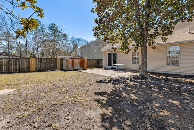 view of yard with a patio area, a fenced backyard, a storage shed, and an outbuilding