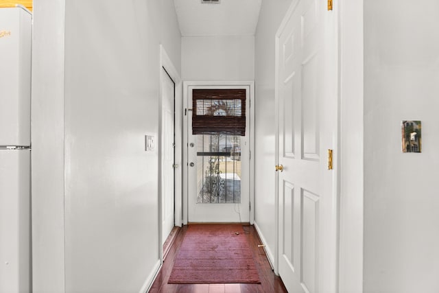 hall with dark wood-style flooring, visible vents, and baseboards