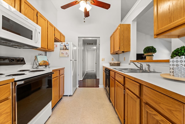 kitchen with white appliances, brown cabinetry, a ceiling fan, light countertops, and a sink