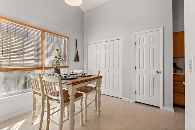 dining room featuring a towering ceiling and baseboards