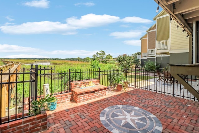 view of patio with an outdoor fire pit, a rural view, and fence