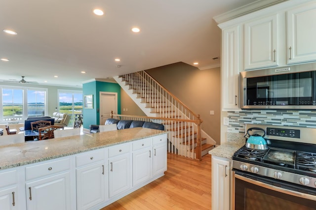 kitchen with recessed lighting, decorative backsplash, appliances with stainless steel finishes, light stone countertops, and light wood-type flooring