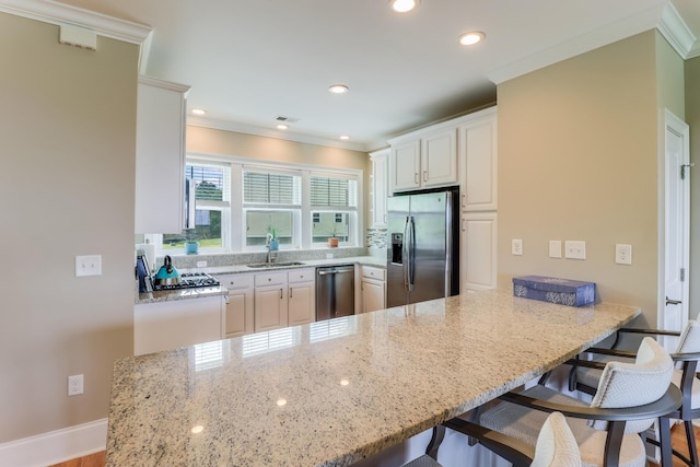 kitchen with appliances with stainless steel finishes, a breakfast bar, a peninsula, and light stone counters