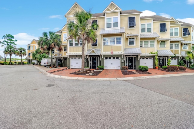 townhome / multi-family property featuring a garage, a residential view, and a standing seam roof