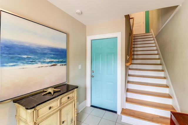 foyer featuring light tile patterned flooring, baseboards, and stairs