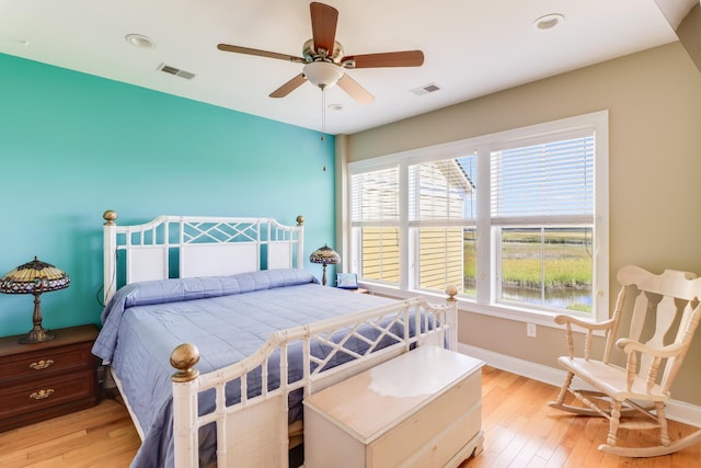 bedroom with light wood-style flooring, a ceiling fan, visible vents, and baseboards