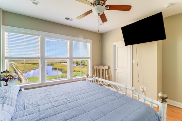 bedroom with ceiling fan, light wood-type flooring, visible vents, and baseboards