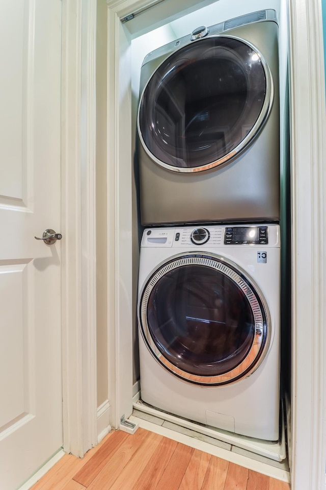 washroom featuring laundry area, wood finished floors, and stacked washer / drying machine