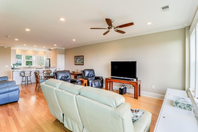 living area featuring baseboards, visible vents, light wood-style flooring, crown molding, and recessed lighting