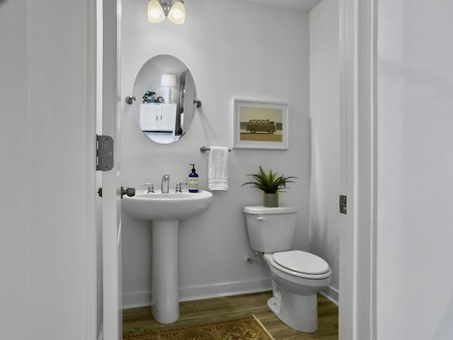 bathroom with toilet, baseboards, and wood finished floors