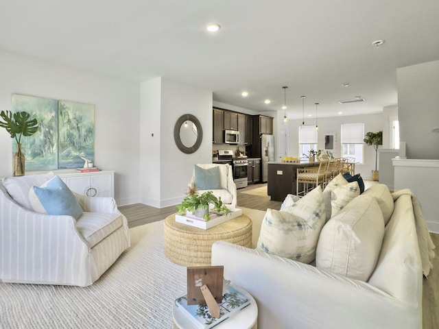 living area featuring light wood finished floors, baseboards, and recessed lighting