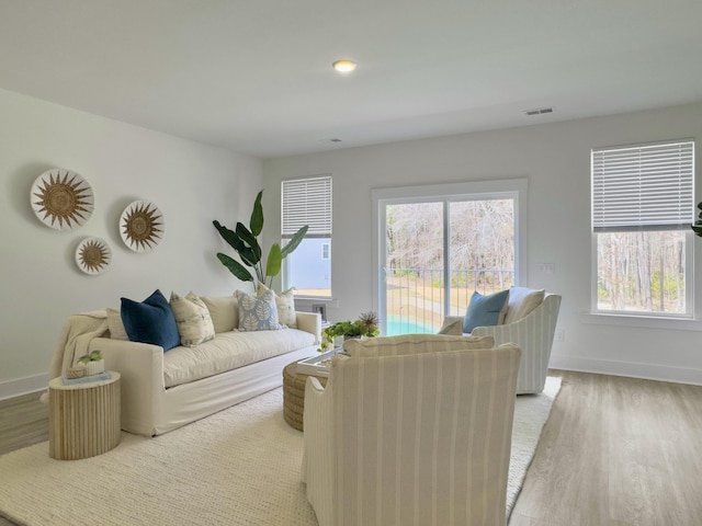 living area with recessed lighting, visible vents, baseboards, and wood finished floors