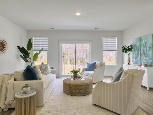 living room featuring baseboards, visible vents, and light wood finished floors