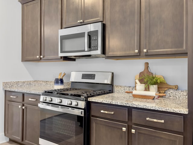 kitchen with light stone countertops, dark brown cabinetry, and stainless steel appliances