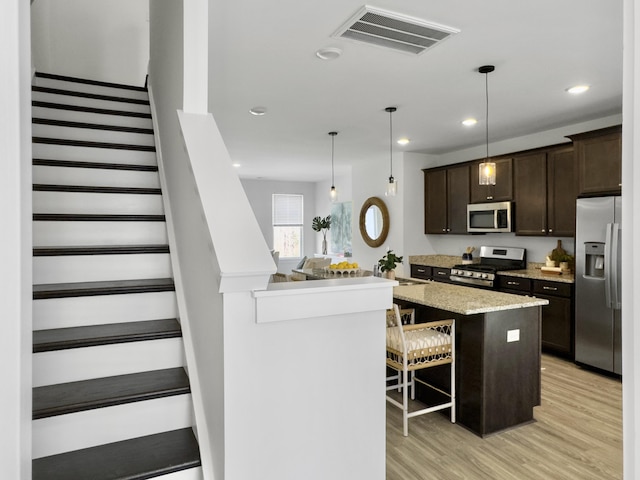 kitchen with dark brown cabinetry, visible vents, stainless steel appliances, light wood-type flooring, and a sink