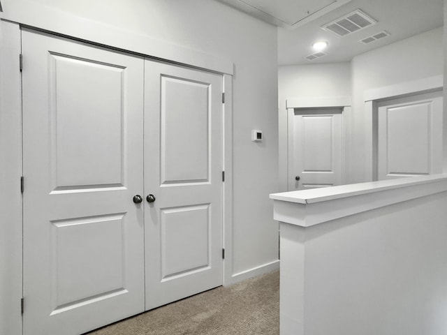 corridor featuring light carpet, attic access, visible vents, and baseboards