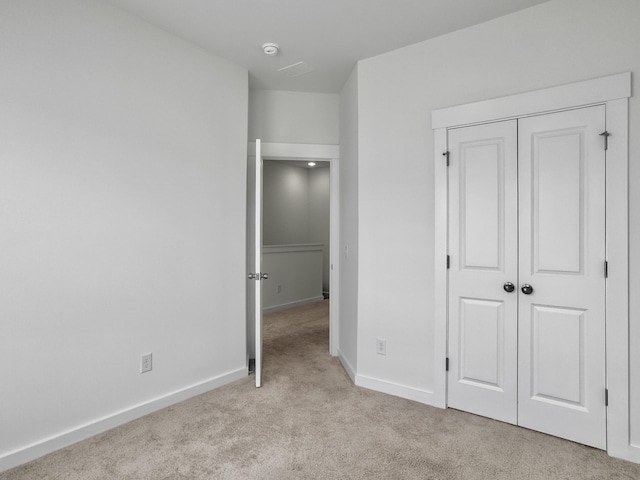 unfurnished bedroom with carpet floors, a closet, and baseboards