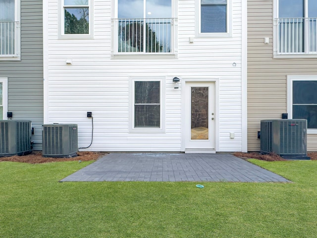 back of house featuring central AC unit and a lawn