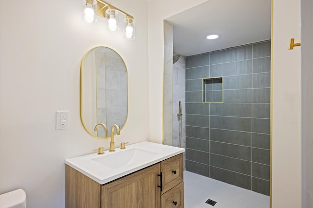 bathroom featuring vanity, toilet, and a tile shower