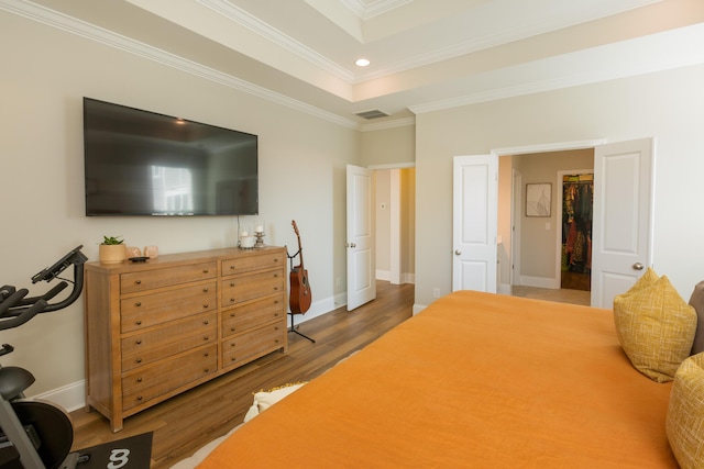 bedroom with crown molding, hardwood / wood-style floors, and a tray ceiling