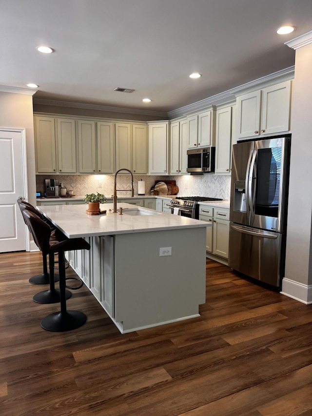 kitchen featuring sink, dark hardwood / wood-style flooring, ornamental molding, a kitchen island with sink, and stainless steel appliances