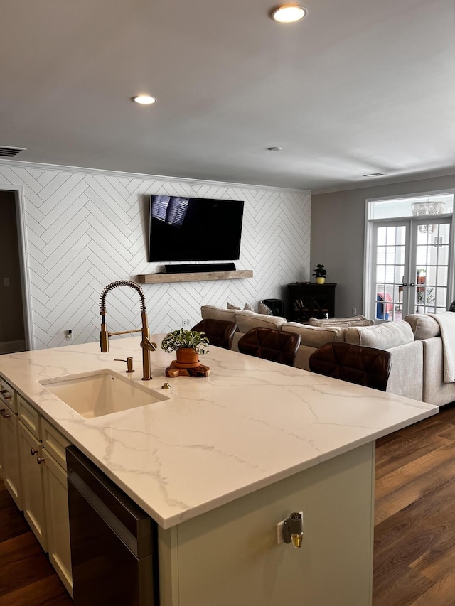 kitchen with sink, dishwasher, a kitchen island with sink, light stone counters, and french doors