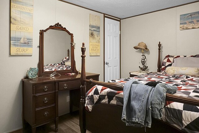 bedroom with a textured ceiling, dark wood-type flooring, and ornamental molding