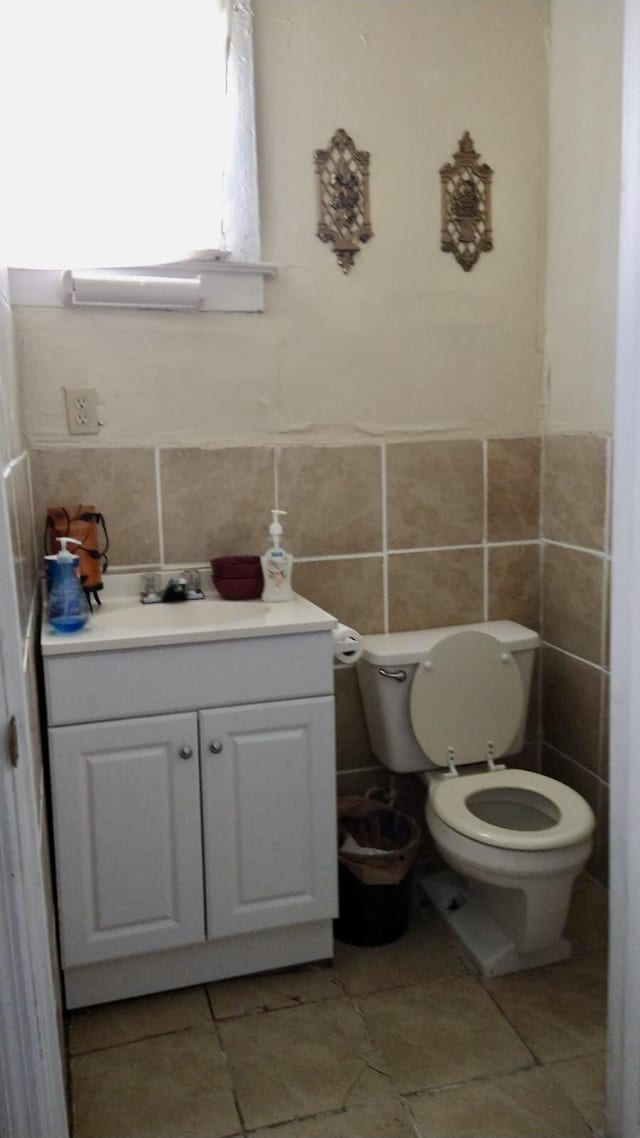 bathroom with vanity, tile walls, and toilet