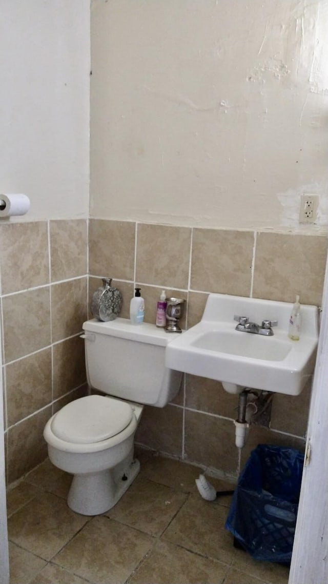 bathroom with tile patterned floors, toilet, sink, and tile walls